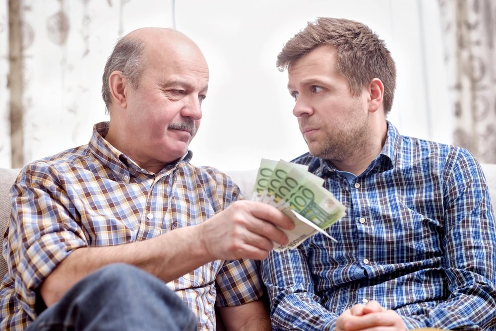 Close-up of hands exchanging money, symbolizing asset transfers relevant to Medicaid eligibility and elder law estate planning.
