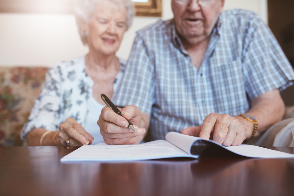 An elderly person with dementia reviews and signs estate planning documents with a legal advisor, emphasizing the need for mental competency in creating a valid will.