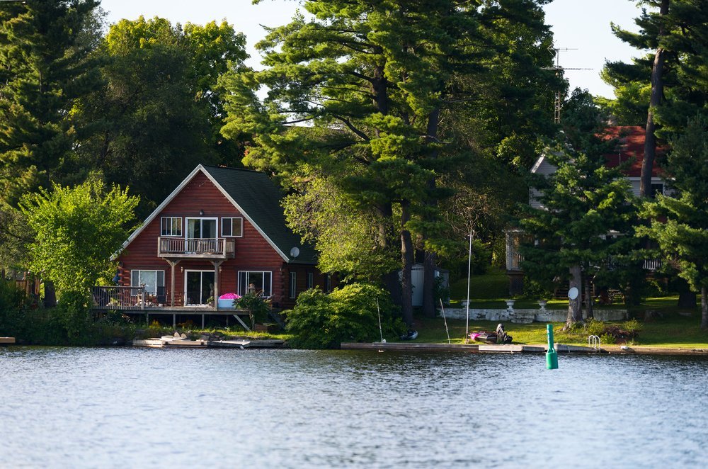 A beautiful vacation house by a lake surrounded by trees, illustrating the complexities and considerations of estate planning and taxes when inheriting real estate.