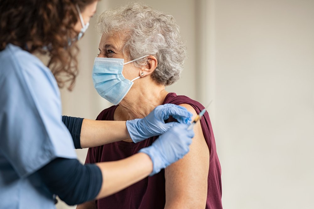 A healthcare professional administers a COVID-19 vaccine to a nursing home resident, highlighting the ongoing efforts to protect elderly individuals and facilitate safer visitation opportunities.