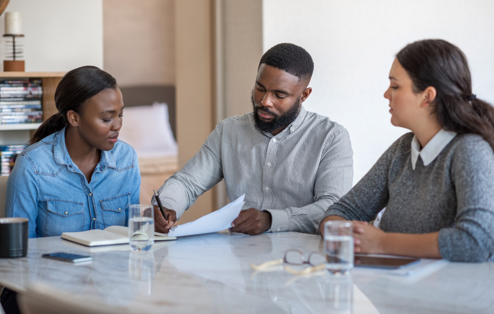A young couple discussing estate planning documents, reflecting the trend of younger adults increasingly preparing wills as per a recent survey.