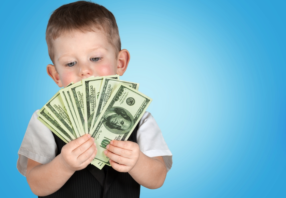 A young girl holds a stack of cash with a concerned expression, representing the complexities of naming minors as beneficiaries in estate planning and elder law issues.