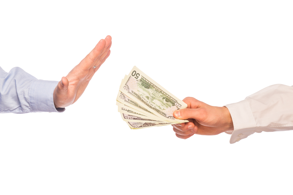 A person hesitantly refusing a bundle of cash, symbolizing the complexities involved in dealing with an unwanted inheritance in estate planning.