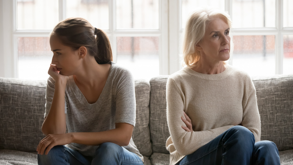 A distressed elderly parent contemplating estate planning with family photographs, symbolizing the emotional challenges of including estranged children in estate decisions.