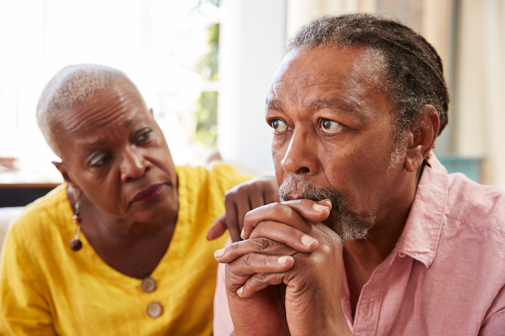 An elderly woman gently comforts an elderly man, illustrating the personal and emotional challenges families encounter when dealing with dementia and Alzheimer’s, important considerations in estate planning and elder law.