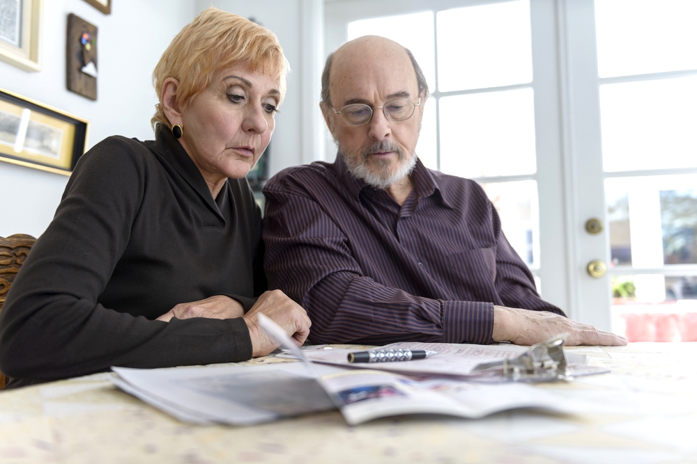 Senior couple examines paperwork with attorney in office, discussing power of attorney revocation and estate planning issues.