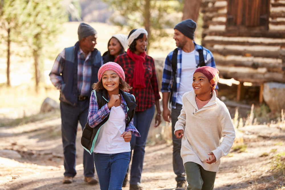 A multigenerational family walking through a forest during fall, representing the concept of estate planning and the transfer of property to heirs through a Qualified Personal Residence Trust (QPRT).