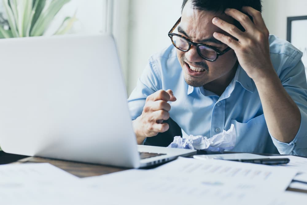 Frustrated businessman at a desk cluttered with paperwork, illustrating the complications of using free Power of Attorney forms in estate planning and elder law contexts.