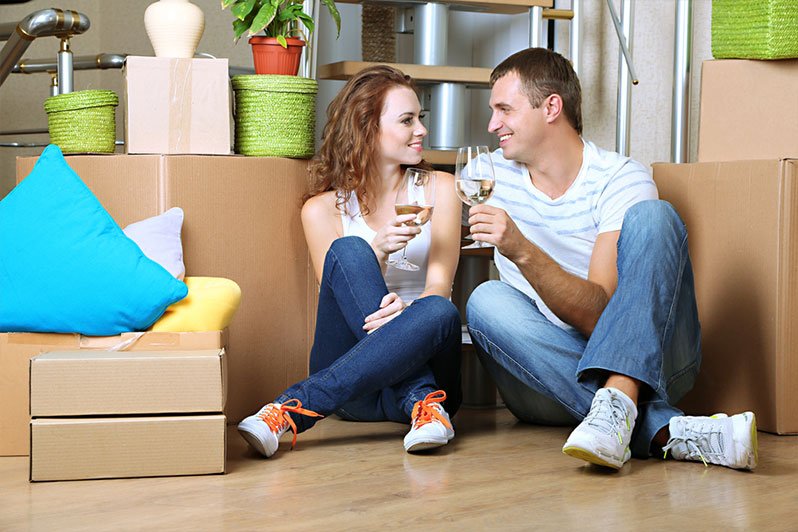 A newly married couple happily discussing their estate planning options at home, surrounded by documents and a laptop.