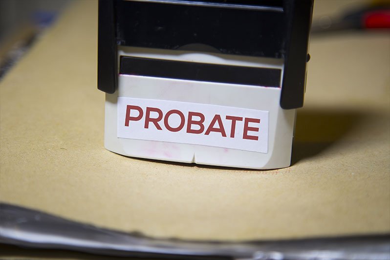 Magnifying glass focusing on the word probate in a document highlighting the importance of avoiding probate through proper estate planning and trust funding.