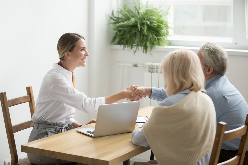 Estate lawyer discussing documents with a senior couple in an office setting, highlighting the importance of professional assistance in estate planning and elder law.