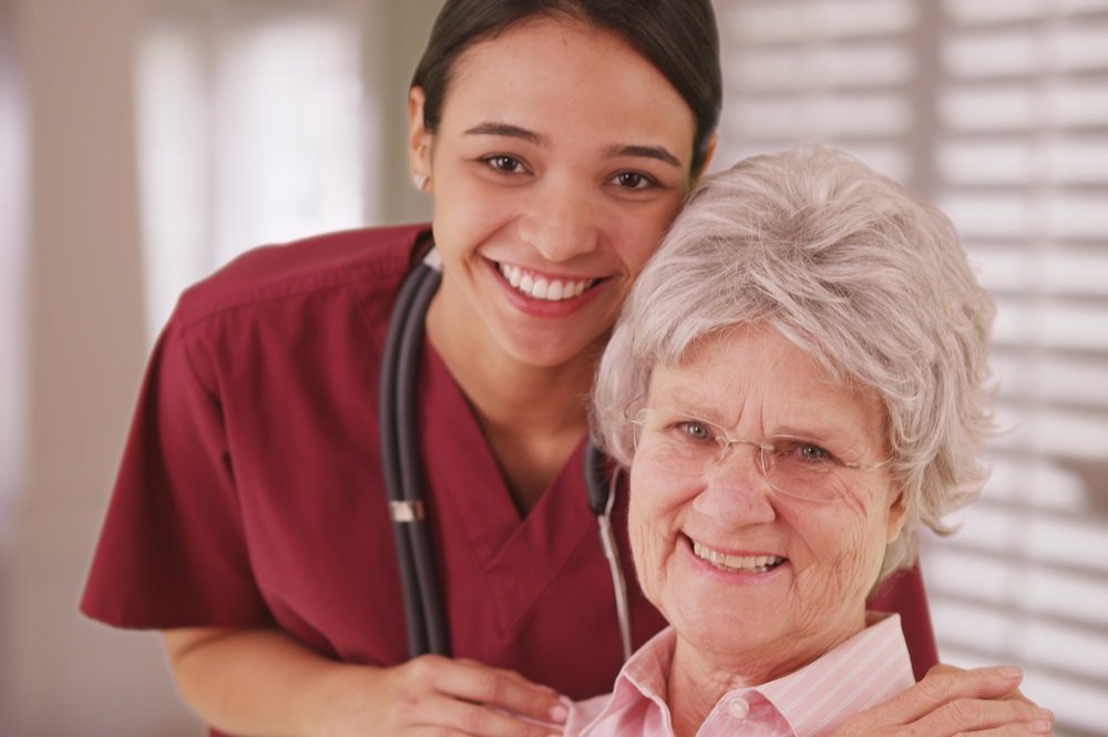 A stressed caregiver sitting beside an elderly woman, emphasizing support for family caregivers in estate planning and elder law.
