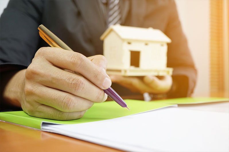 Close-up of a person writing on a legal deed document, highlighting the potential risks of drafting property deeds without professional help in estate planning and elder law contexts.