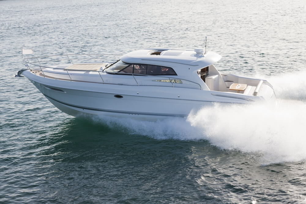 White motor yacht traveling quickly on the water, creating a trail of foam behind it, symbolizing the concept of boat ownership through a living trust.