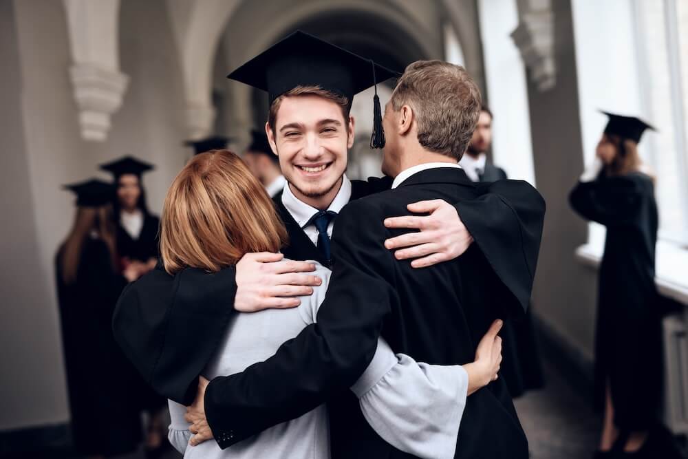 Newly graduated student hugging parents, illustrating the significance of a Power of Attorney once a child turns 18.