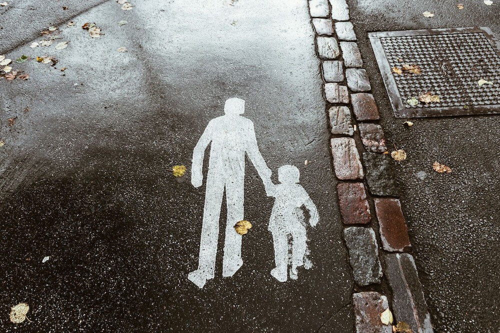 Pavement marking of an adult and child holding hands, symbolizing guidance and protection.