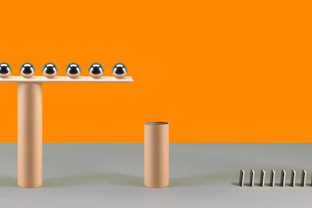 Abstract illustration showing balance and stability — metallic spheres aligned on a wooden beam supported by cardboard tubes, symbolizing structure and precision in trust planning.
