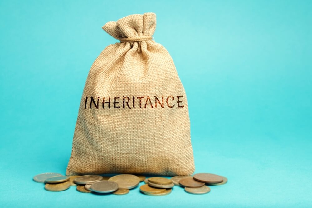 Cloth bag labeled "Inheritance" surrounded by scattered coins on a blue background